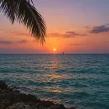 A sunset over the sea with a distant sailboat